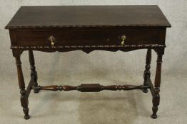 An early 20th century oak single drawer side table with brass swing handles, raised turned