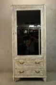 A 20th century single mirrored door hanging wardrobe above two drawers with brass handles raised
