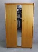 A mid 20th century Schreiber twin door wardrobe with central mirrored panel raised on square