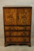 An early 20th century walnut twin door tallboy opening to reveal single shelf above three graduating