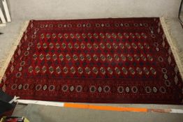 An early 20th century Persian woollen rug with allover gul motifs on a burgundy field. L.280 W.