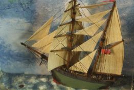 A contemporary three dimensional diorama of a boat on the sea, in a square driftwood style frame.