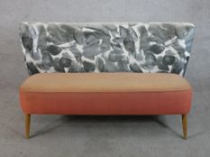 A mid 20th century, possibly Ercol wing back two person settee, raised on splayed tapering supports.