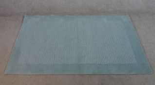 A contemporary John Lewis duck egg blue handmade woollen rug. W.108 L.169cm