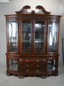 A large 20th century mahogany four glazed door bombe shaped display cabinet raised on three