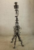 A late 19th/early 20th century painted wrought iron floor standing candle holder raised on four