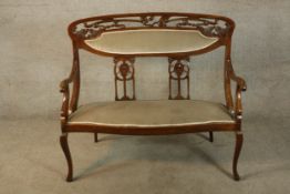 An Edwardian mahogany framed pierced splat back open arm upholstered settee raised on cabriole