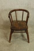 A 19th century beech childs bow shaped spindle back chair raised on splayed supports and 'H'