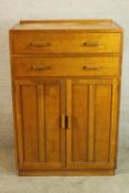 A mid 20th century Ernst Gomme oak two drawer over two panel door tallboy raised on plinth base. H.