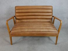 A 20th century Datsun teak framed ribbed brown leather open arm settee raised on tapering