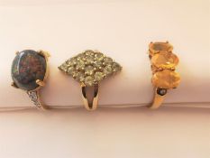 Three 20th century 9 carat yellow gold gem-set rings: a sugar treated black opal and diamond flanked