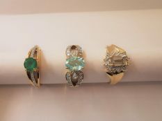 Three 20th century 18 carat yellow gold gem-set rings: a diamond and emerald flanked solitaire ring,