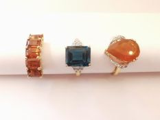 Three 20th century 10 carat gold gem-set rings: a blue topaz flanked solitaire ring, a diamond and