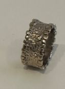 A bark textured brutalist design 9 carat white gold band. Hallmarked 9 carat and with indistinct