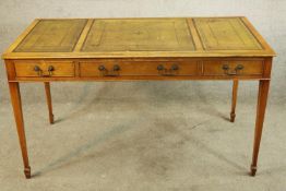 A Georgian style walnut writing table with three drawers raised on tapering supports terminating