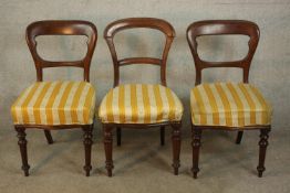 A pair of Victorian walnut dining chairs, upholstered in white and yellow striped fabric, on