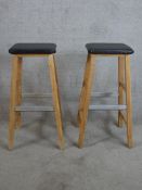 A pair of contemporary pine and leather stools raised on square splayed supports with metal foot