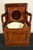 A 19th century mahogany comode with hinged lid opening to reveal open arm open seat. H.48 W.56 D.