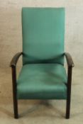 A mid 20th century mahogany effect open arm upholstered nursing chair raised on square supports.