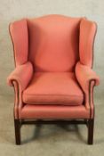 A 19th century mahogany framed upholstered wing back scroll arm chair raised on square supports. H.