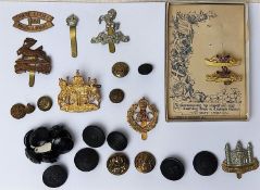 A collection of military cap badges and pressed military uniform buttons.