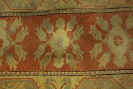 A Persian rug with repeating floral medallions on a terracotta ground. L.146 W.84cm.