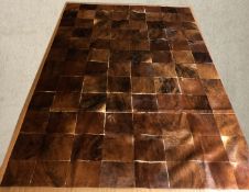 A large carpet made from cow skin patches. L.356 W.237cm.