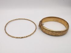 Two 9ct yellow gold bangles. A hollow engraved scrollwork clip bangle with safety chain (broken).