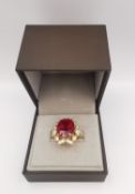 A boxed 18 carat yellow gold ruby and diamond cocktail ring. Set to centre with a cushion shaped