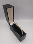 A boxed 9ct yellow gold textured and engraved bangle with a hidden pin clasp with safety catch.