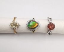 Three 20th century 9 carat gold gem-set rings. An ammolite and diamond drop cluster ring, a topaz