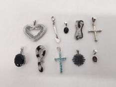 A collection of ten gem set silver pendants with various designs. A green stone heart pendants, a