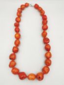 A 20th century knotted orange coral bead necklace, comprising of twenty irregular polished beads.