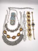 A collection of costume jewellery, including four articulated statement bracelets, a floral form