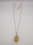 An 18ct yellow gold Ayatul Kursi (throne verse) oval pendant on a 18ct yellow gold box chain.