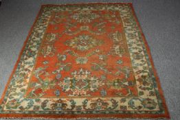 A woollen Turkish rug on terracotta field within foliate borders. L.277 W.190cm.
