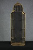 A decorative metal birdcage. With two birds perched outside of the cage. The cage very likely once