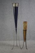 Two large conical pots. The taller in metal and the smaller decorated with carved fish. Both on