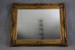 A large wall mirror in gilt foliate frame with bevelled plate. H.128 W.158cm.