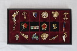 A box of eighteen brooches. A mix of designs and styles including golf and sailing. Housed in a