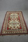 A Turkish Kars rug, stylised borders on a burgundy ground. L.205 W.129cm.