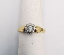 An 18ct yellow and white gold diamond solitaire ring. Set to centre with a round brilliant cut