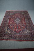 Carpet, a Persian Mashad with central medallion and scrolling flowerhead motifs on a burgundy
