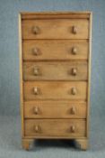 A mid century light oak tall chest, raised on later casters. H.129 W.61 D.41cm.