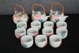 A Chinese tea set made up of twelve cups and three teapots with wooden handles. H.15cm. (largest)