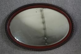 A wooden framed oval mirror. H.70 W.100 cm.