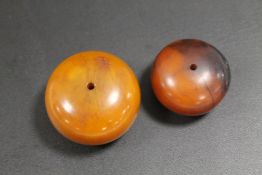 TWO LARGE AMBER TYPE BEADS