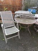 A METAL CIRCULAR PATIO TABLE WITH FOUR RECLINING CHAIRS