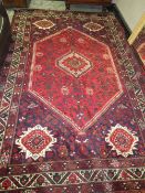 A LARGE EASTERN WOOLLEN RUG - MAINLY RED AND BLACK 305 X 203CM
