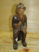A CARVED WOODEN FIGURE OF A SEATED MAN